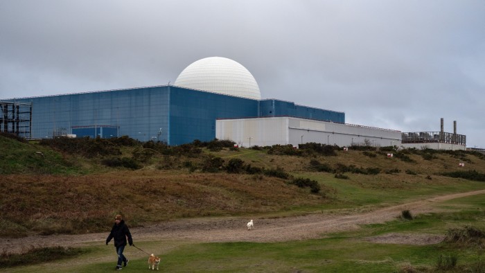 A man walking a dog past Sizewell B nuclear power station at Sizewell in Suffolk, England