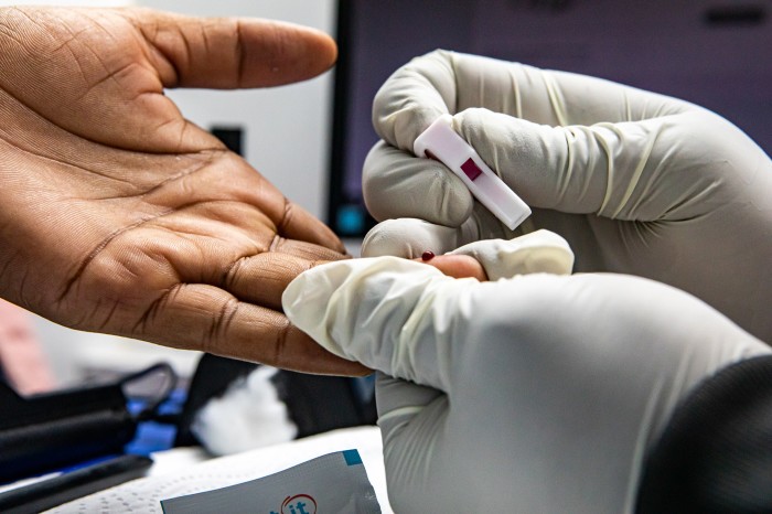 A healthcare worker in a lime-green shirt prepares a syringe with medicine inside a mobile clinic