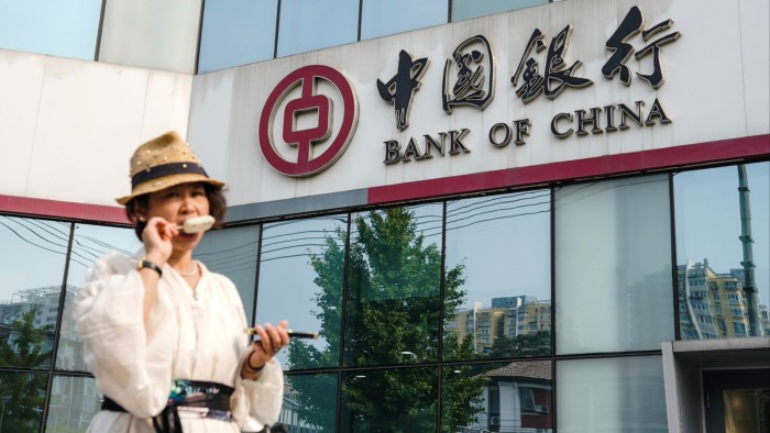 A woman walks outside a Bank of China branch in Beijing
