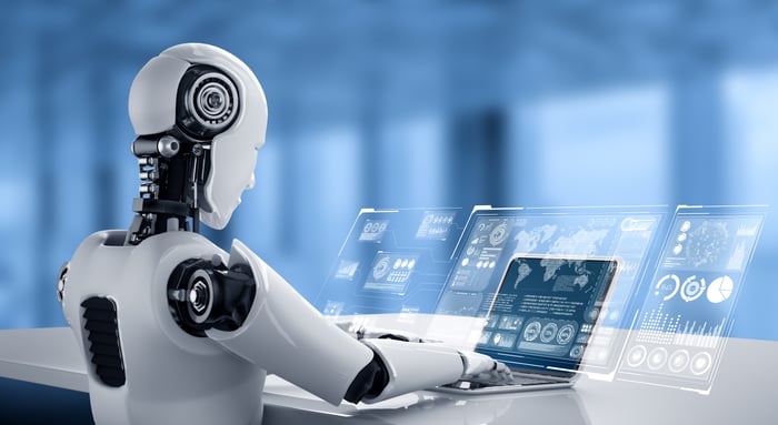 A humanoid robot uses a laptop.