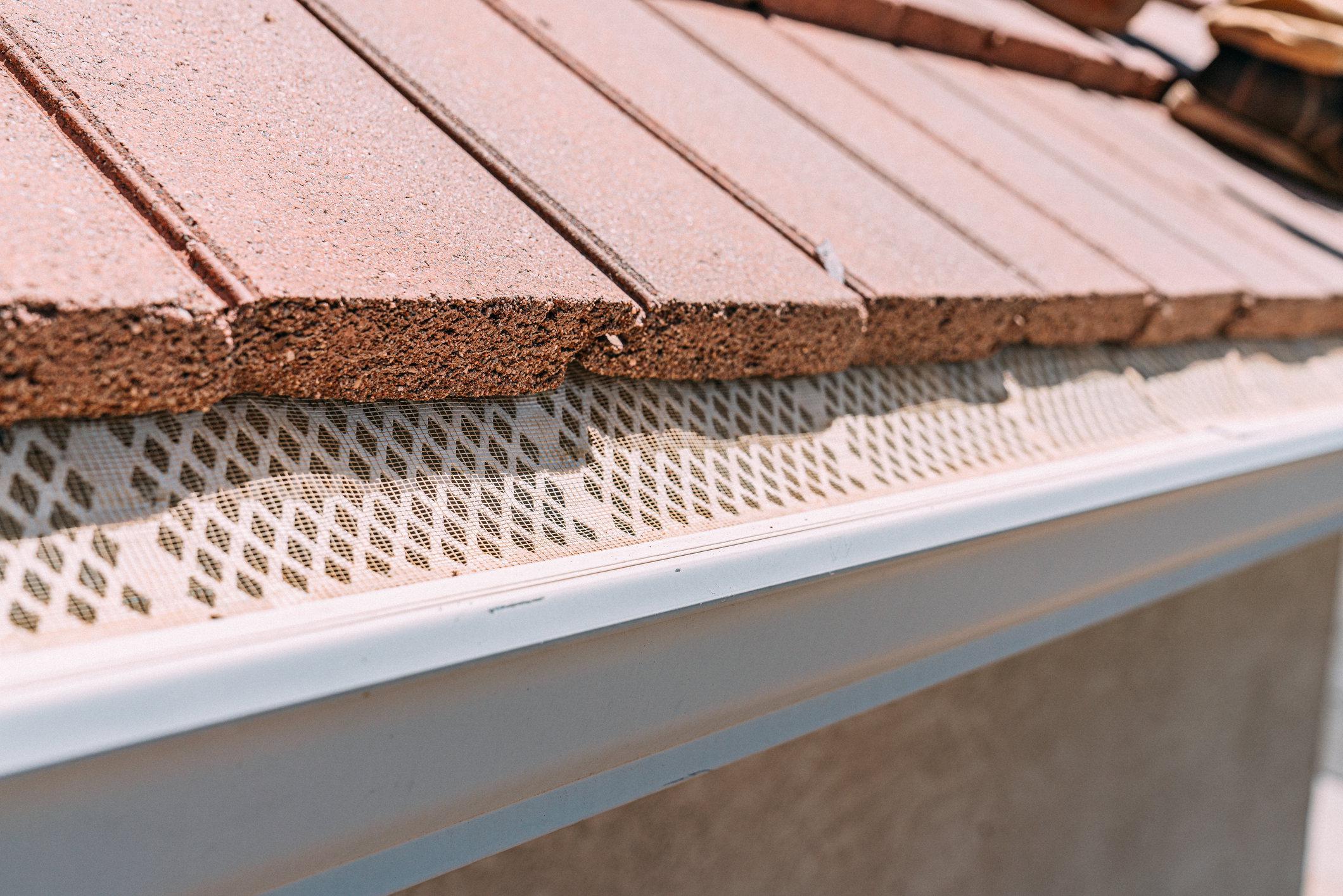 Mesh Guard Protecting an Aluminum Rain Gutter from Debris on a Clay Tile Roof