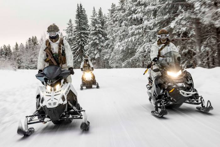 Soldiers conducting a vehicle patrol on snowmobiles in Sweden