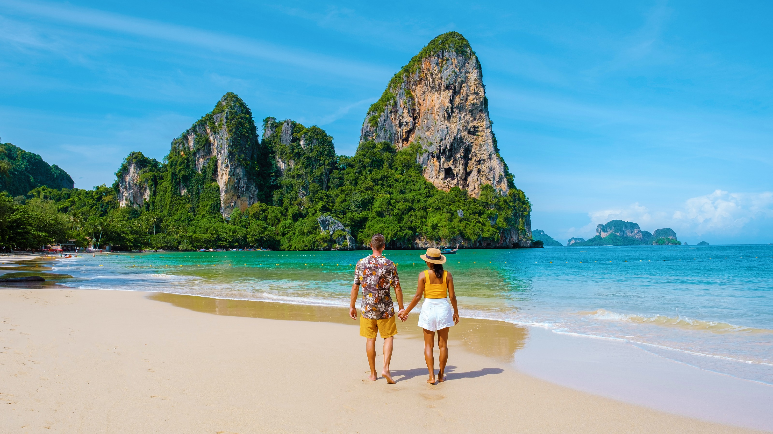 A couple walk hand in hand on a beautiful beach.