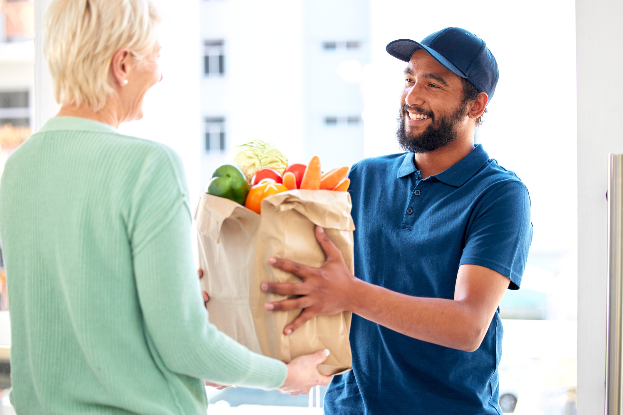 Man is delivering groceries to a woman at her front door.
