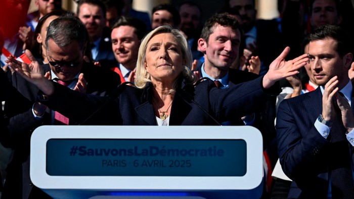 Jordan Bardella applauds as Marine Le Pen gestures after delivering a speech during a rally in her support