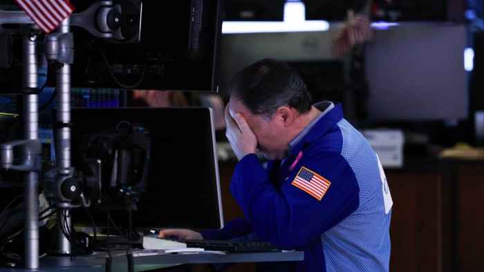 Trader holds head in hands on stock exchange floor
