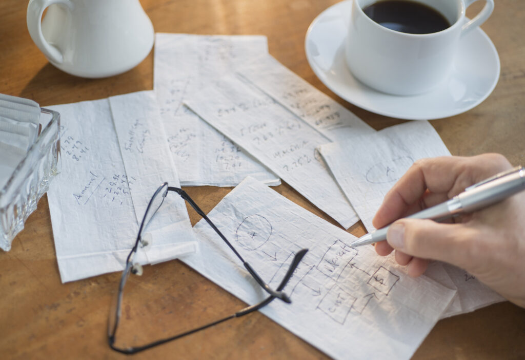 Hand drawing calculations on paper napkin.