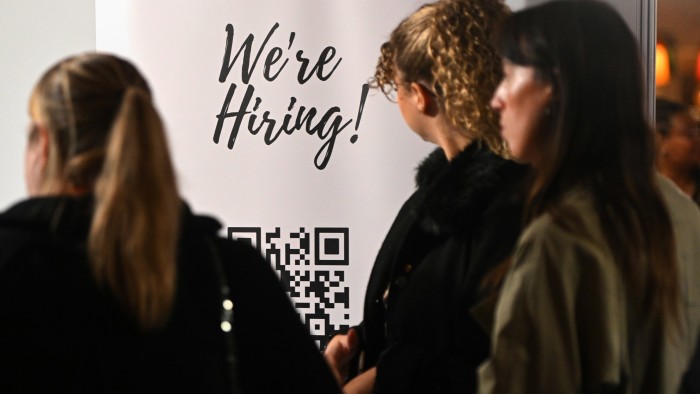 Three young girls standing next to a sign saying ‘We’re hiring’