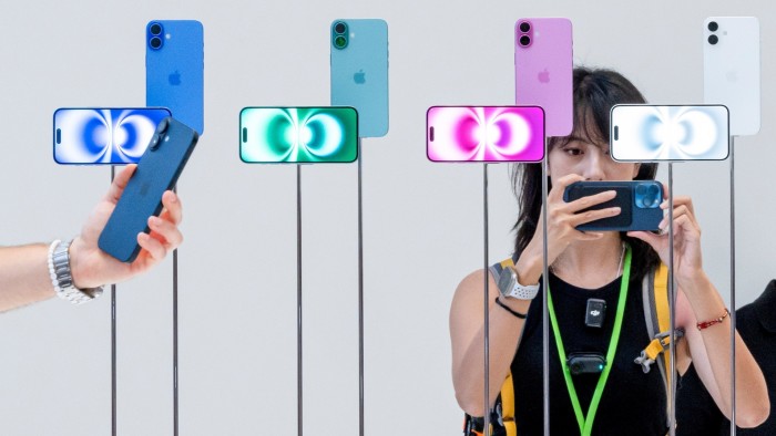 People looking at Apple iPhones on a stand