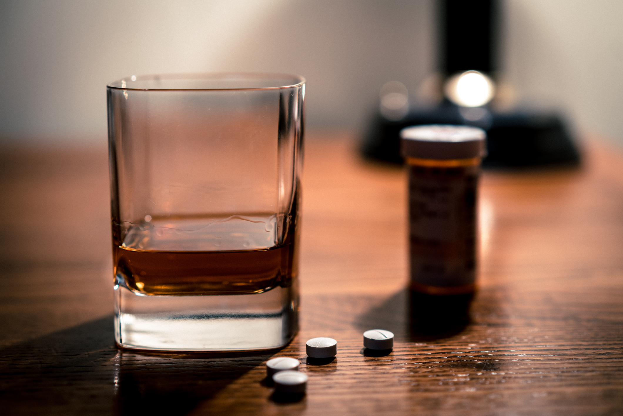 Opiate pills and alcohol epidemic -- close up of pills and glass of booze