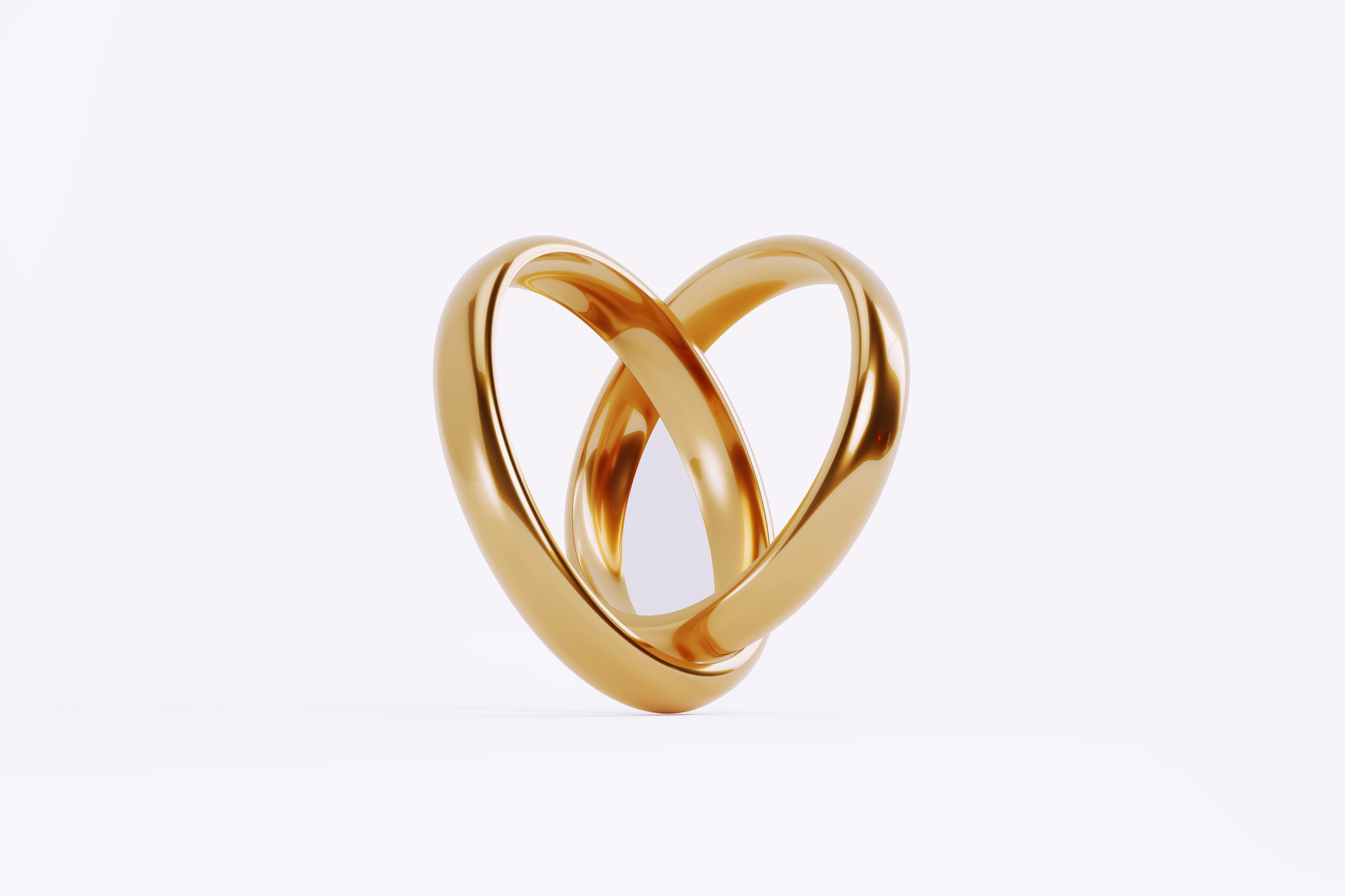 Gold wedding rings forming a heart shape on white background. Great use for wedding, love and romance concepts.