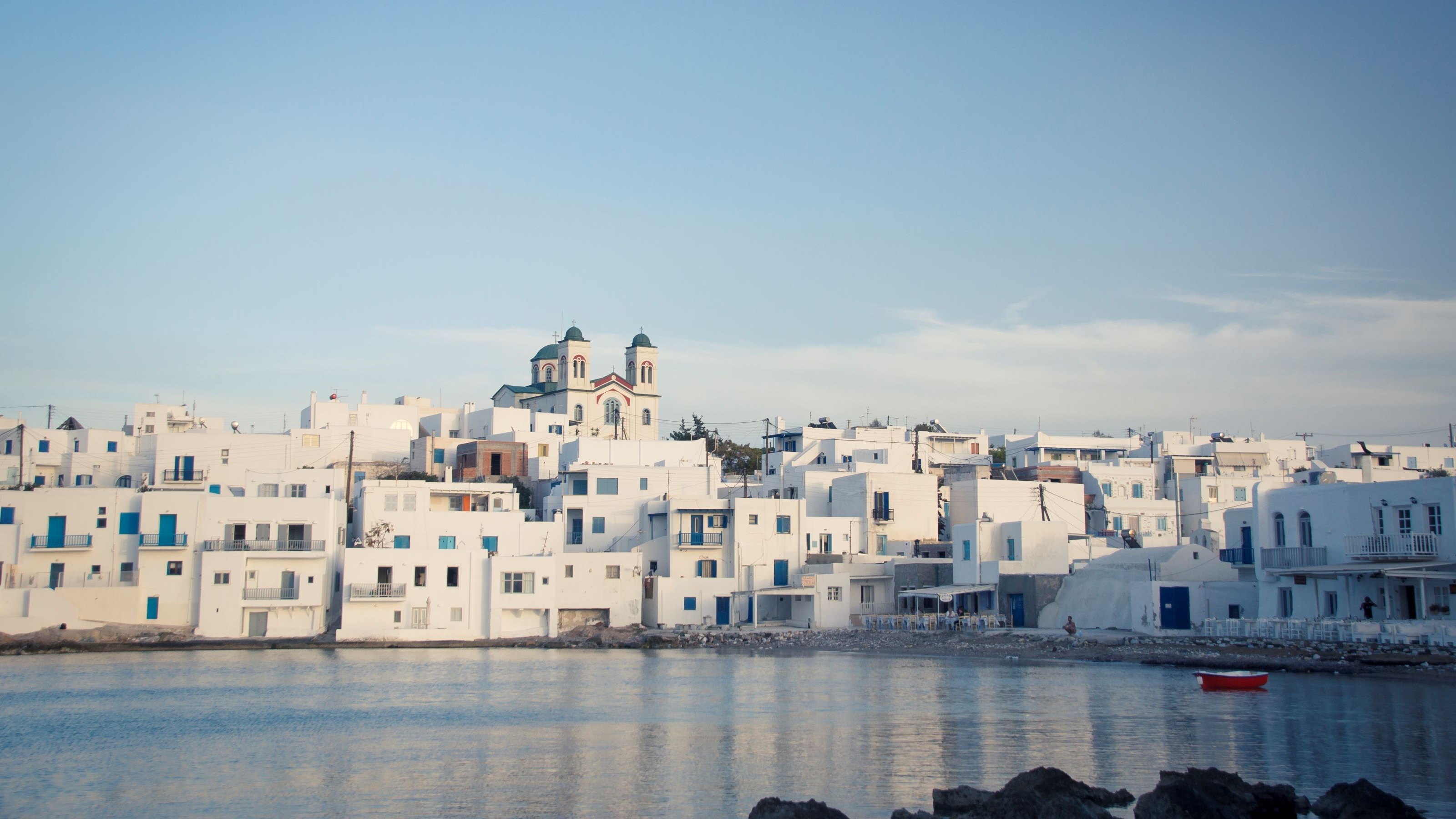 White building with blue accents over the water in Paros, Greece.