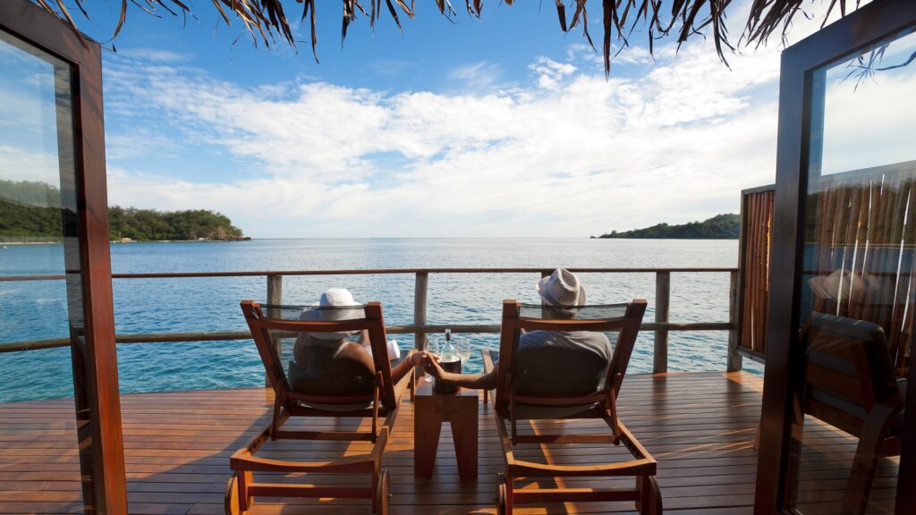 An older couple sitting in beach chairs on a deck looking at the ocean in Fiji