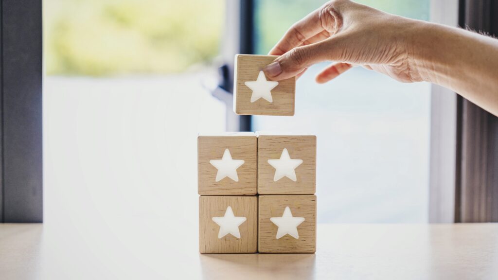 Five wooden blocks with white stars being stacked by a woman.
