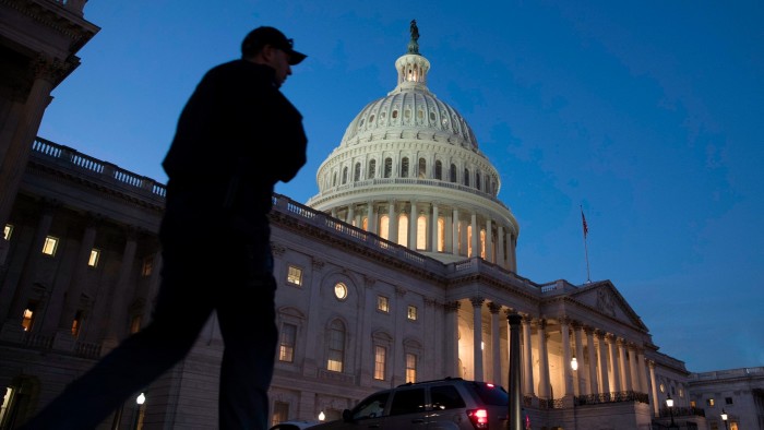 A Capitol police officer walks in front of the Capitol building at dusk
