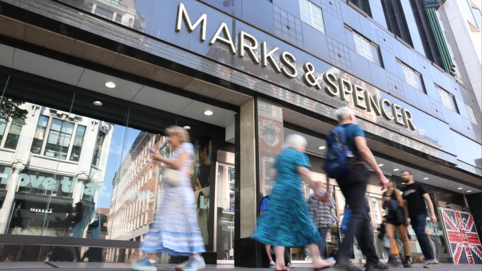 Shoppers walk past a Marks & Spencer retail store in London