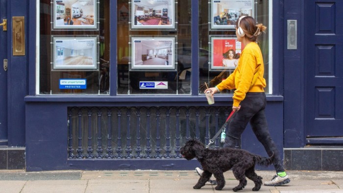 A woman walks past an estate agent office