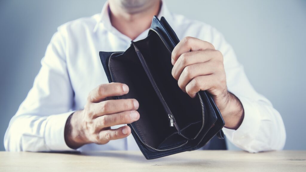 An older man holds up an empty wallet.