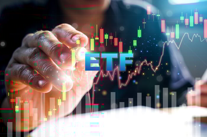 Fingers pointing to a stock chart with ETF in the foreground.