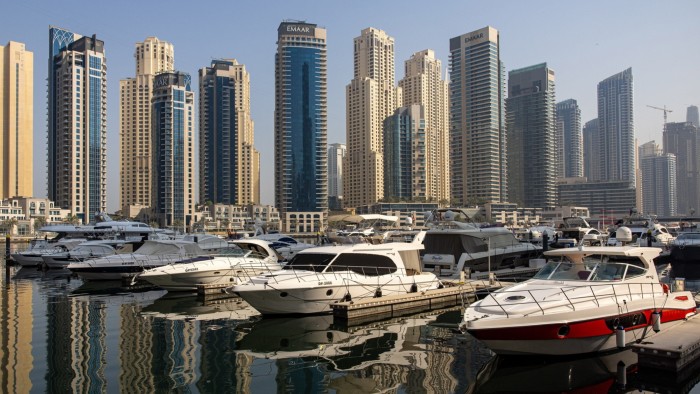 Residential skyscraper buildings beyond motor yachts docked in the Dubai marina district of Dubai, United Arab Emirates