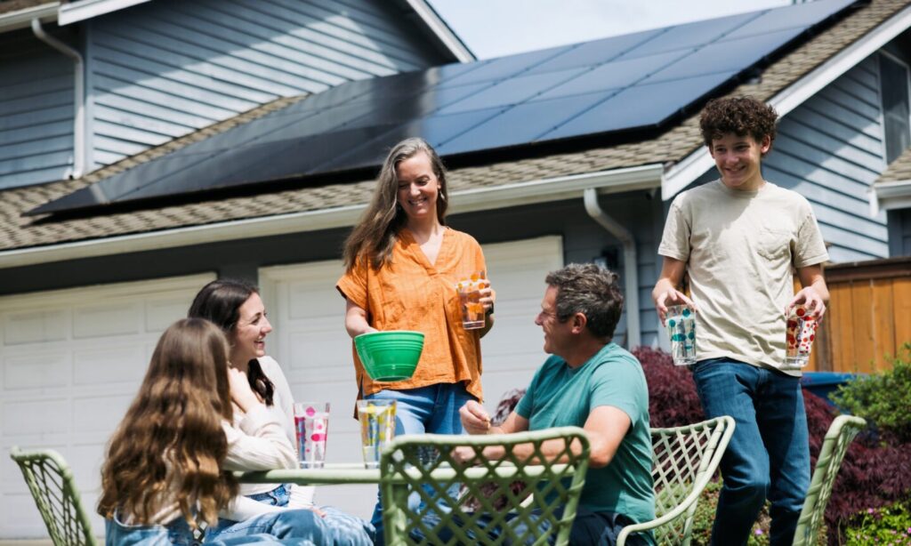 Family at table outdoors near home with solar panels