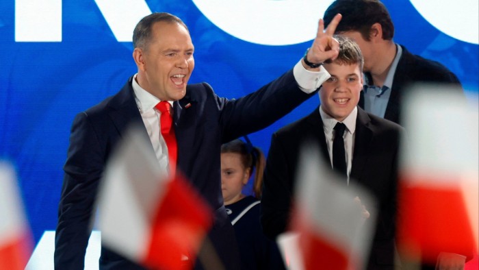 Karol Nawrocki shows a victory sign in front of supporters during election night