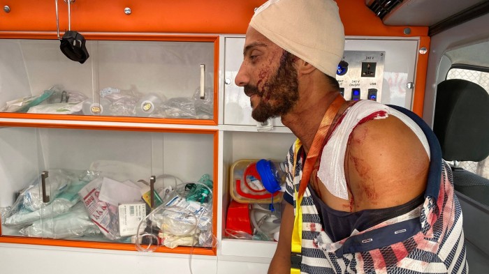 A man, with bandages on his head and shoulder, sits inside an ambulance