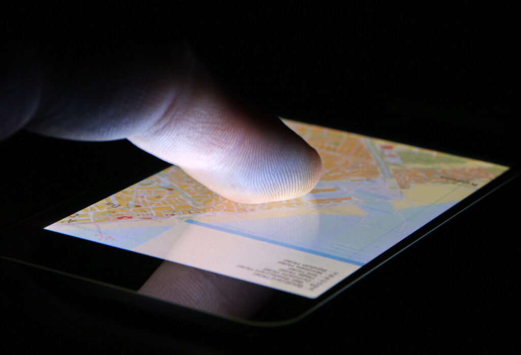 Finger touching navigation map on a touch screen smartphone device to demonstrate dementia hot spots.