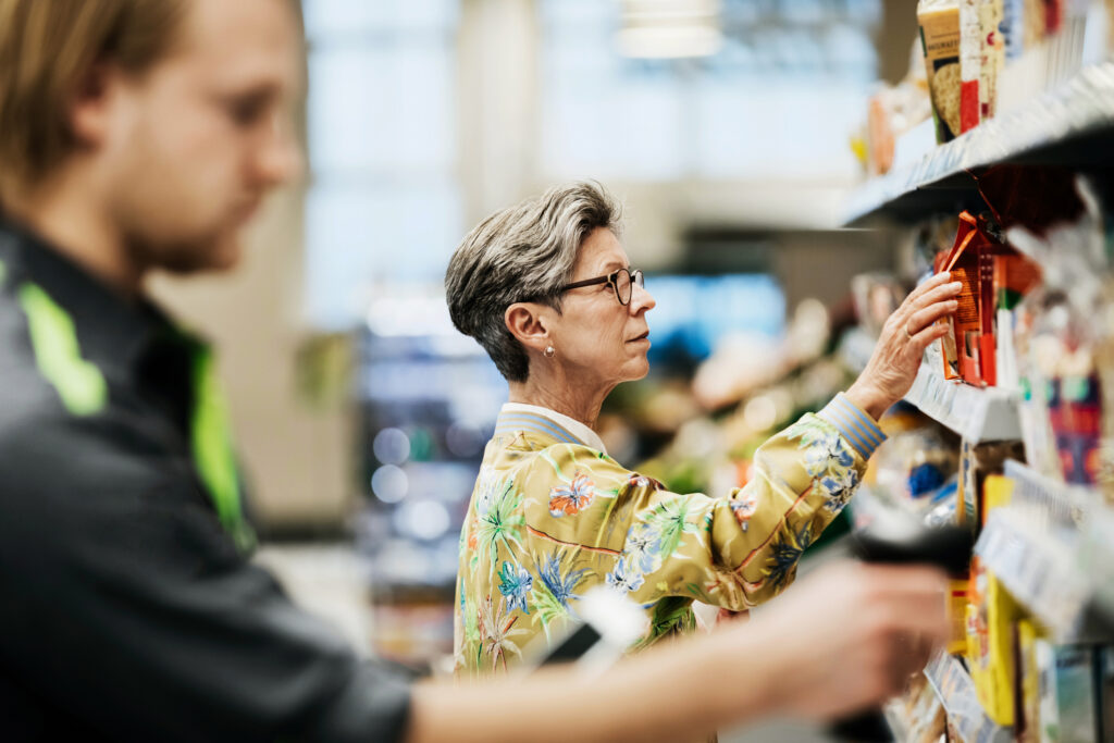 Woman Picking Goods From Shelf At Supermarket