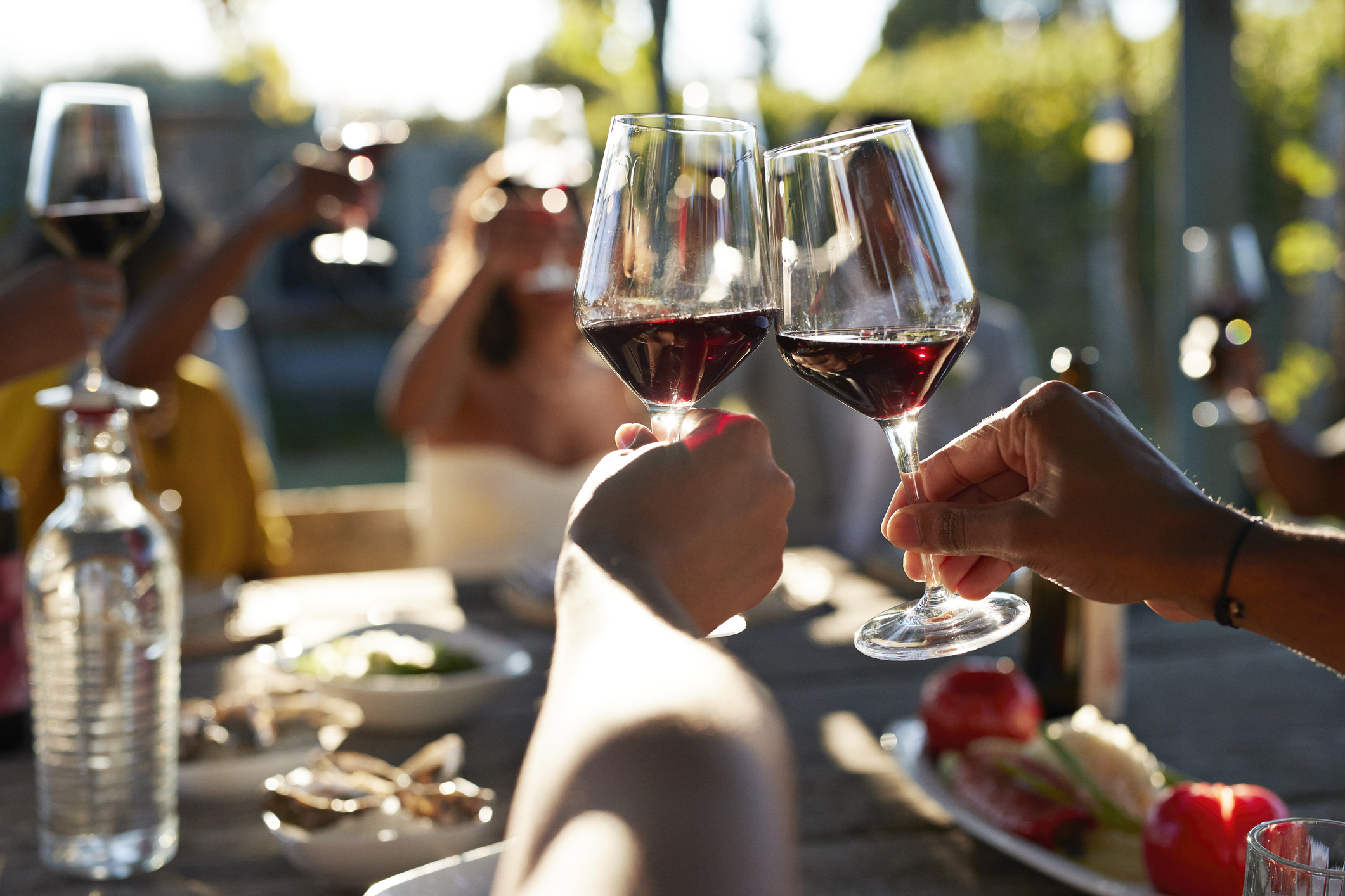 Friends toasting glasses with red wine.