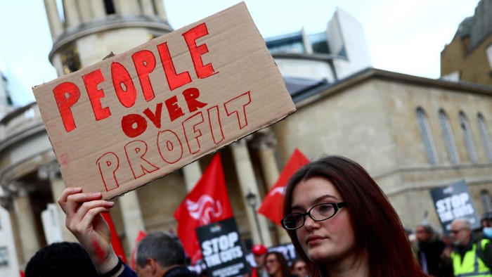 A protester holds a banner that reads ‘people over profit’ during a protest over benefits cuts