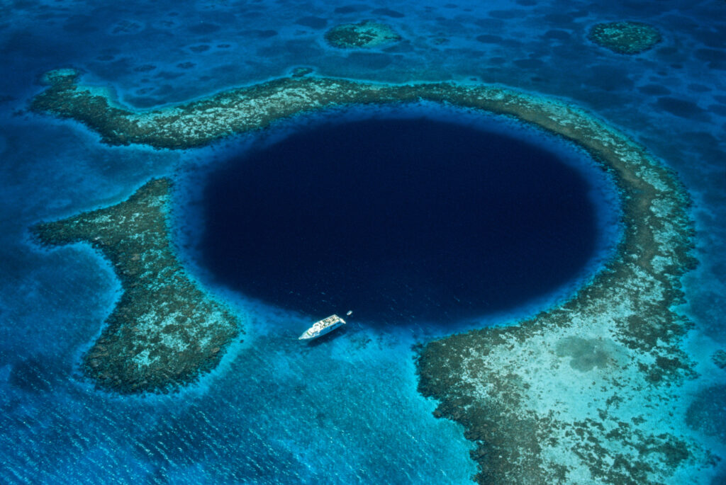 Belize, Lighthouse Reef, boat moored at Blue Hole, aerial view.
