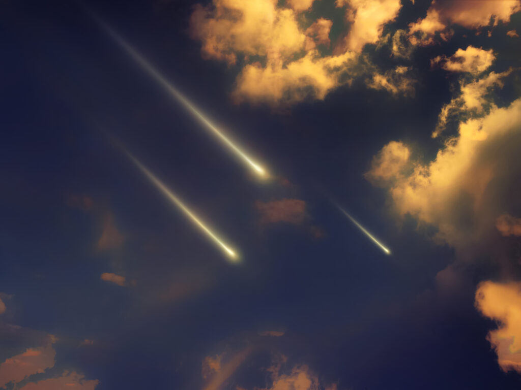 Three fireballs falling from the sky at sunset.