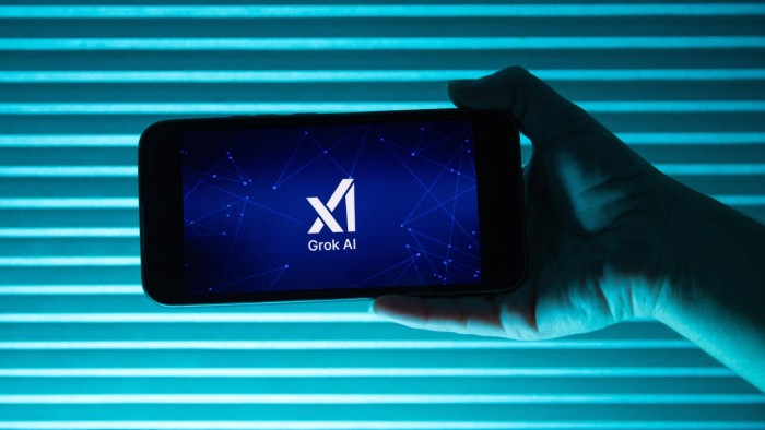 A person holds a telephone displaying the logo of Elon Musk s artificial intelligence XAI