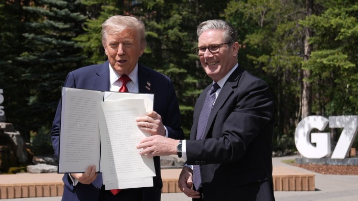 US President Donald Trump (left) holding a US-UK trade deal with Prime Minister Sir Keir Starmer while speaking to the media at the G7 summit in Canada on Monday