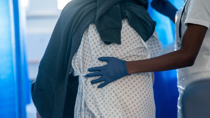 NHS staff guides a patient through a hospital ward