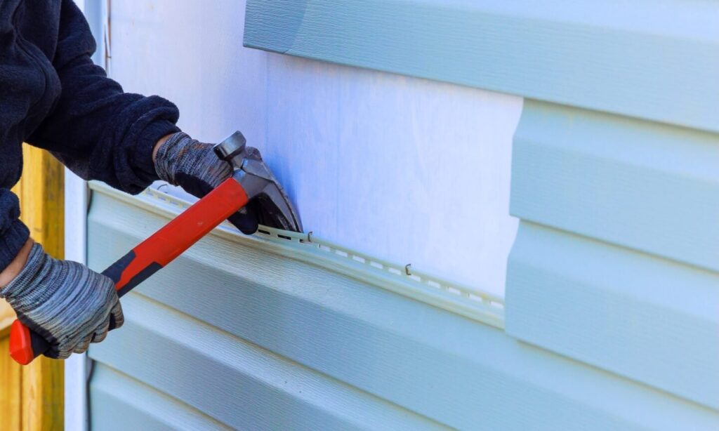 Worker replacing vinyl siding on house