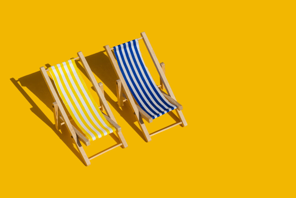 a yellow beach chair next to a blue beach chair