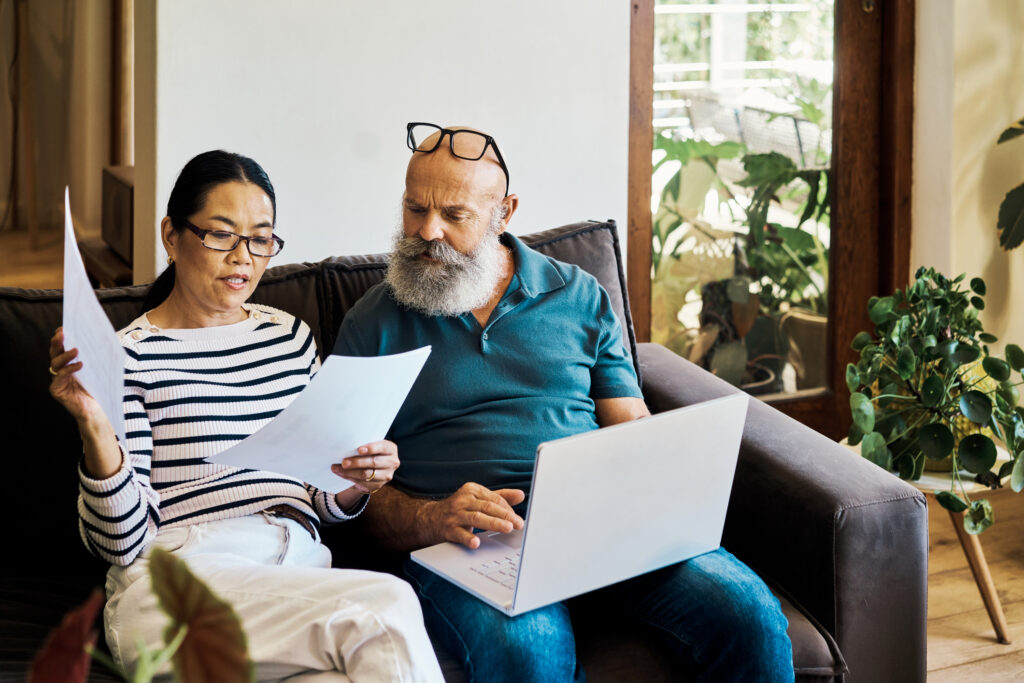 A couple discussing their finances sitting on a couch with a laptop
