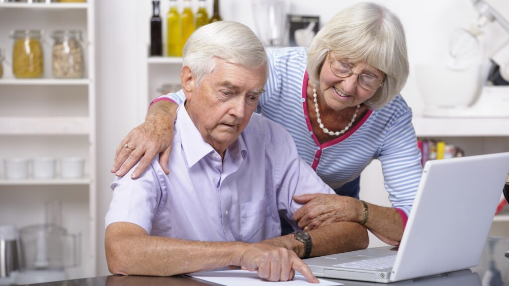 An older couple at home looking at a computer.