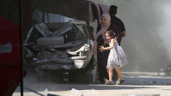 A Palestinian mother and her daughter rush for cover during an Israeli strike at a refugee camp in the central Gaza Strip on July 4 2025