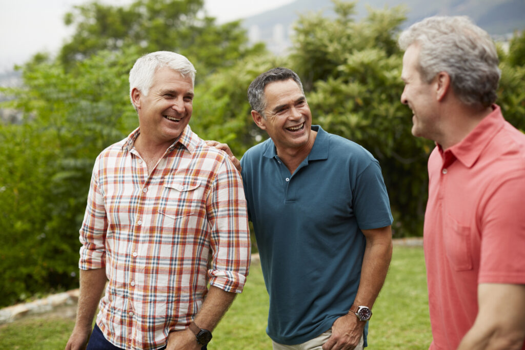 Happy mature male friends spending leisure time in park. The men are in their late 50s or early 60s.