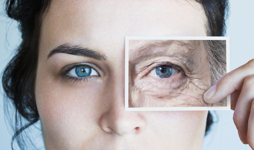Young woman with photo of aged eye over her own.