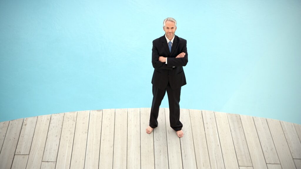 A businessman stands by a pool.
