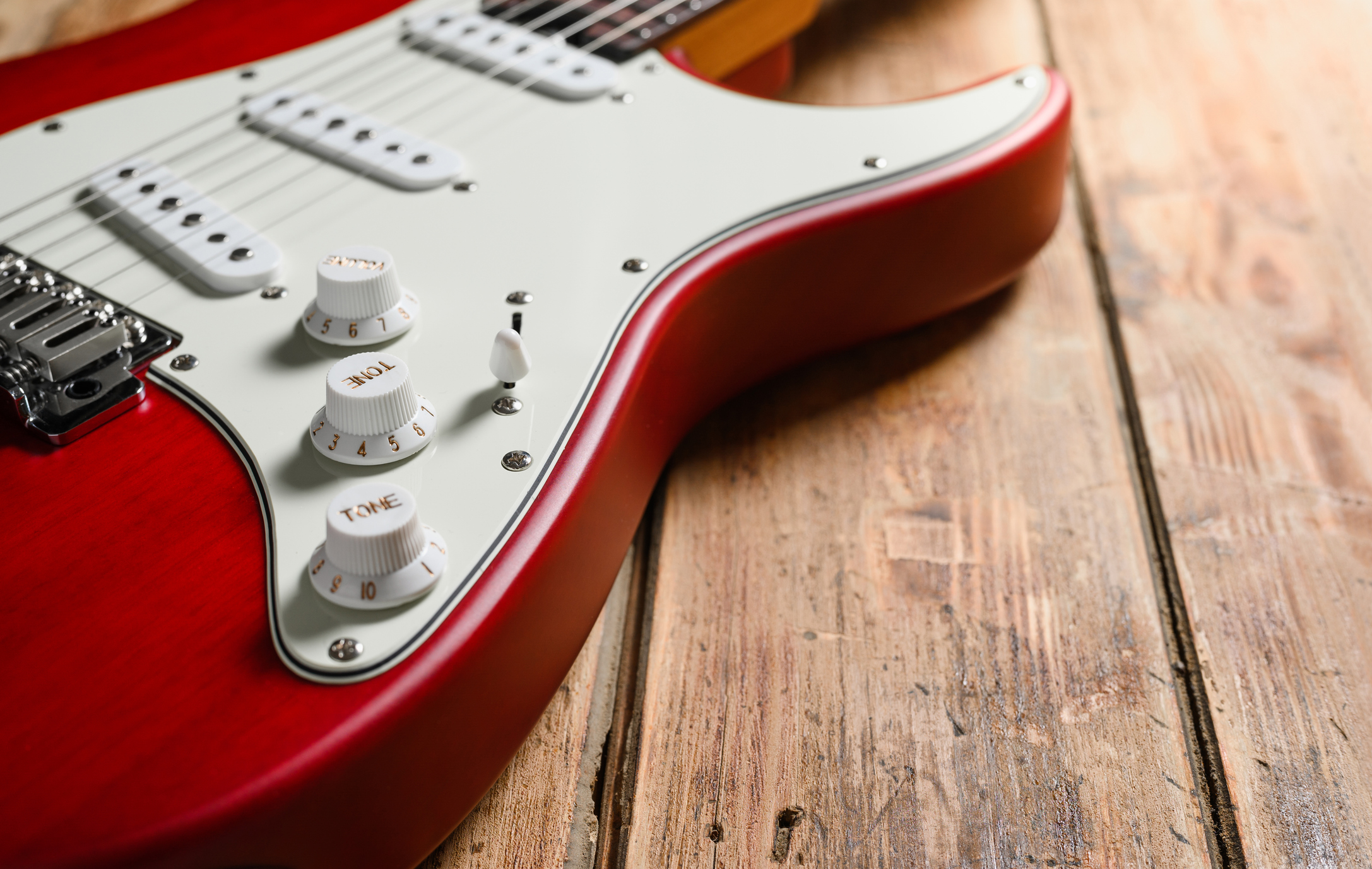 close-up of a retro red electric guitar on a wood floor