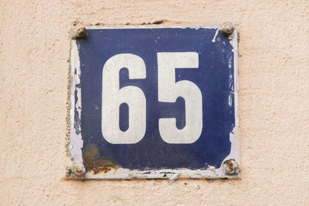 the number 65 on a metal plate against a peach background