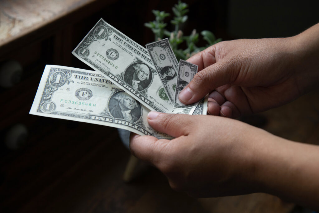 Hands holding shrinking dollar bills, inflation concept.