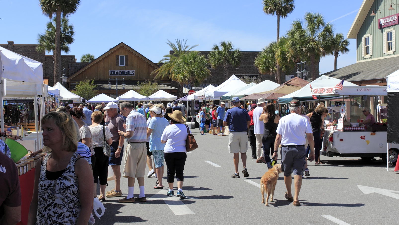 The Villages, FL, USA - April 1, 2017: Street market shops under canopies sell to shoppers on a sunny day. People at the Farmers' market shops near Paddock Square.