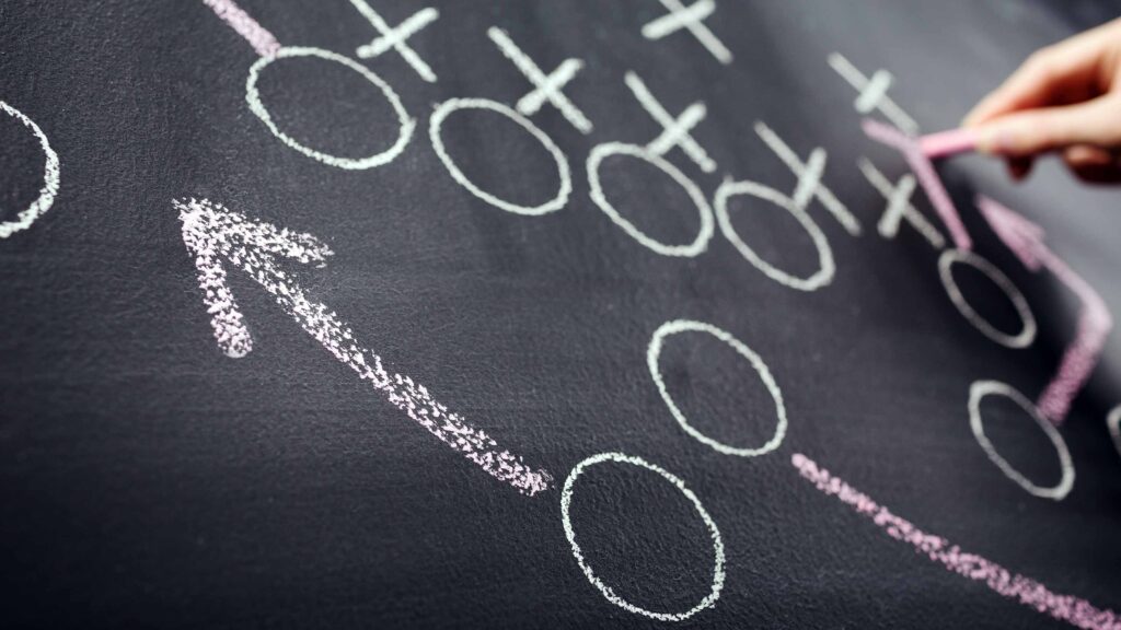 person drawing football plays on chalkboard