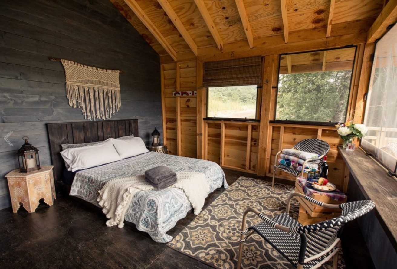 A charming suite in a cabin-like structure at Paint Rock Farm. The room has high, wooden ceilings, a king-size bed and view.